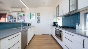 Una cocina moderna con armarios blancos, un lavamanos de acero inoxidable y un horno empotrado.