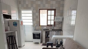 A modern kitchen with a built-in oven and microwave, a dining area with a table and chairs, and a large sofa in the living area. - Angra Sol e Mar Suite: rest, comfort and enchanting beaches. Close to Brasfels. (Angra dos Reis)