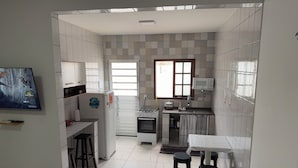 A compact kitchen with a refrigerator, stove, microwave, and a small dining area with stools. - Angra Sol e Mar Suite: rest, comfort and enchanting beaches. Close to Brasfels. (Angra dos Reis)