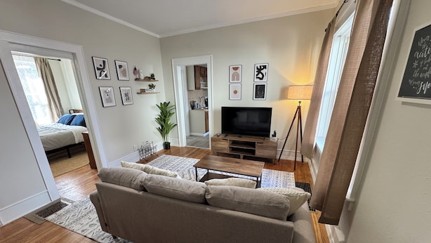 A living room with a sofa, TV, and a small kitchen area.