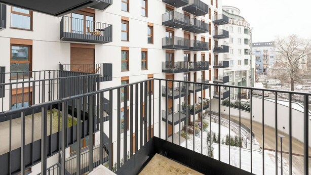 Un moderno edificio de apartamentos con varios balcones, una escalera y vistas del entorno.