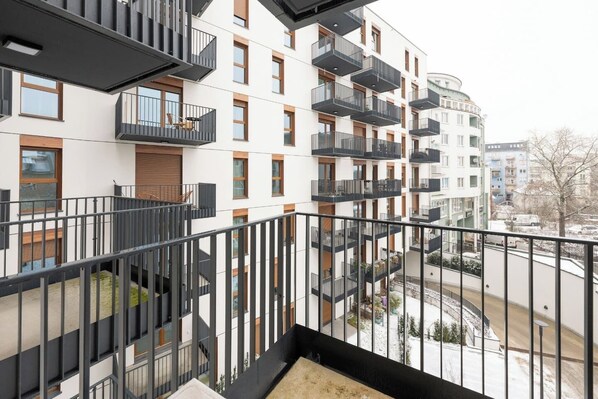 Ein modernes Mehrfamilienhaus mit mehreren Balkonen, einer Treppe und Blick auf die Umgebung.