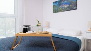 Un dormitorio con cama, mesita de noche y una pintura en la pared, además de una ventana.