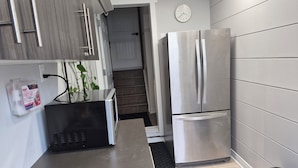 A modern kitchen with stainless steel appliances, a built-in microwave, and a first aid kit on the wall.