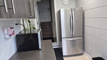 Ett modernt kök med vitvaror i rostfritt stål, en inbyggd mikrovågsugn och ett första hjälpen-kit på väggen.