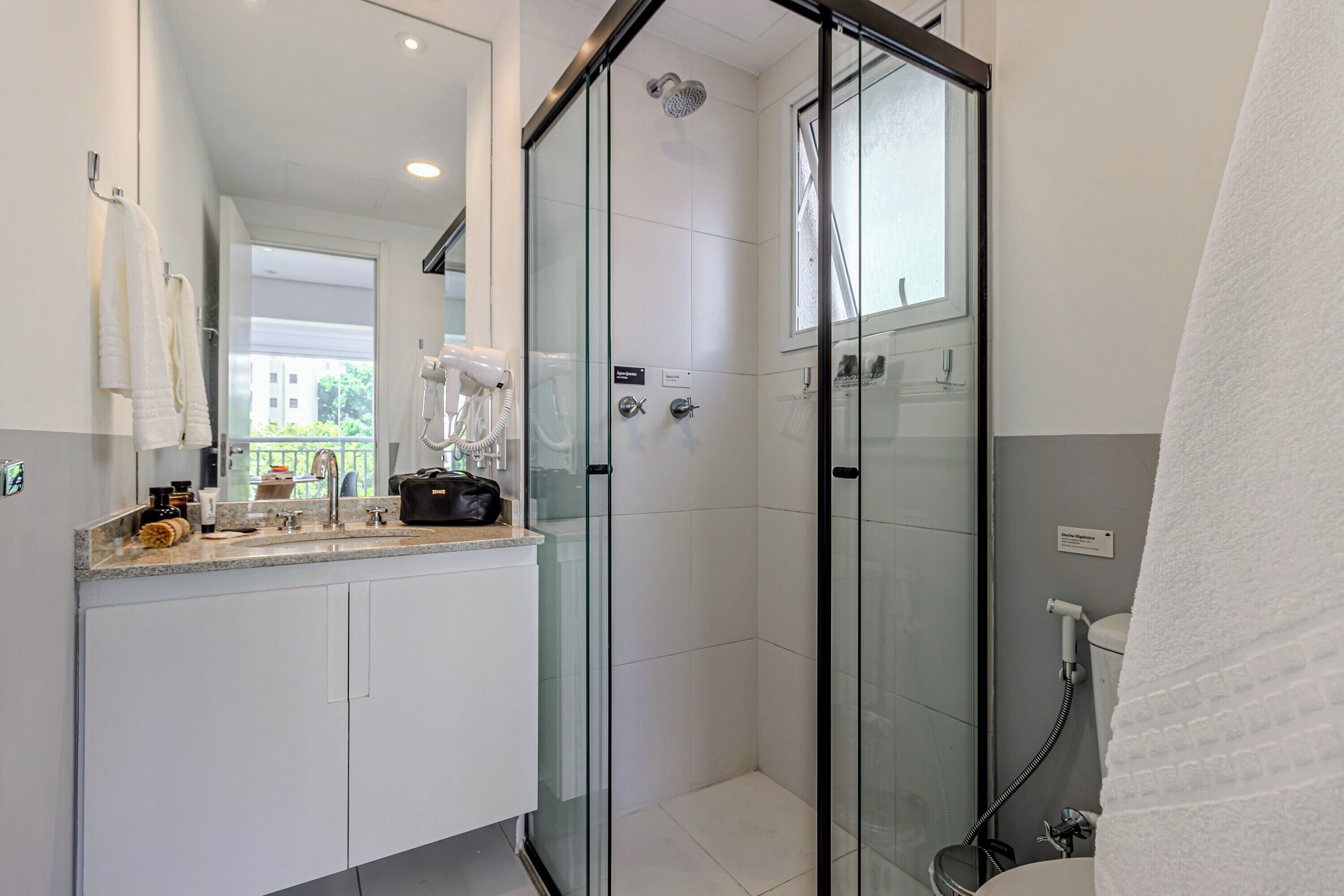 A modern bathroom with a glass-enclosed shower, a vanity with a sink, and a towel rack.