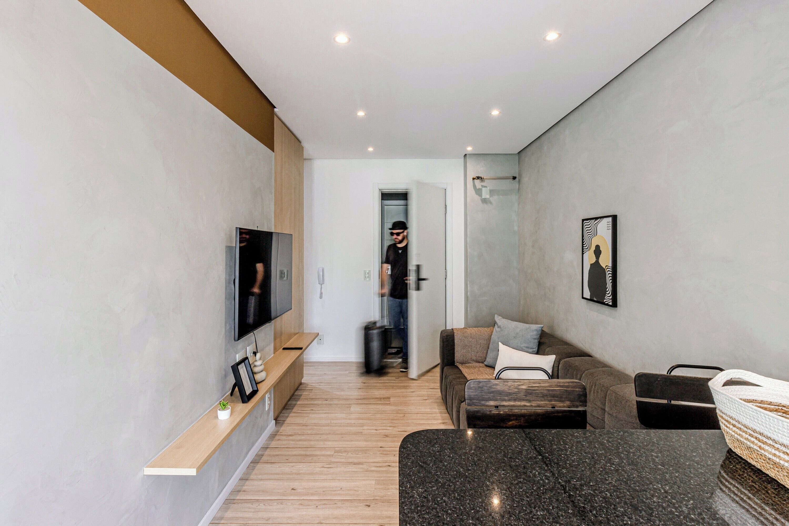 A modern living room with a flat-screen TV, a wooden bench, a sofa, and a coffee table.