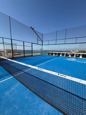 A blue indoor tennis court with a net labeled "PadelGalis." - Beachfront apartment with private jacuzzi (Sin.)