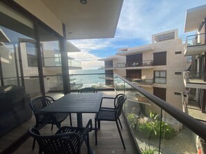 Un balcón con mesa y sillas, con vista al mar.