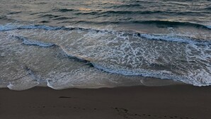 Ein Strand mit Wellen und einem Sonnenuntergang.