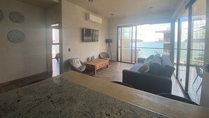 Ein modernes Wohnzimmer mit einem großen Fernseher, einem Holztisch und einer Couch.