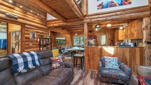 A cozy log cabin interior with a dining area, kitchen, and seating with a view of the outdoors. - Charming year round lake view cabin! (Wakefield)
