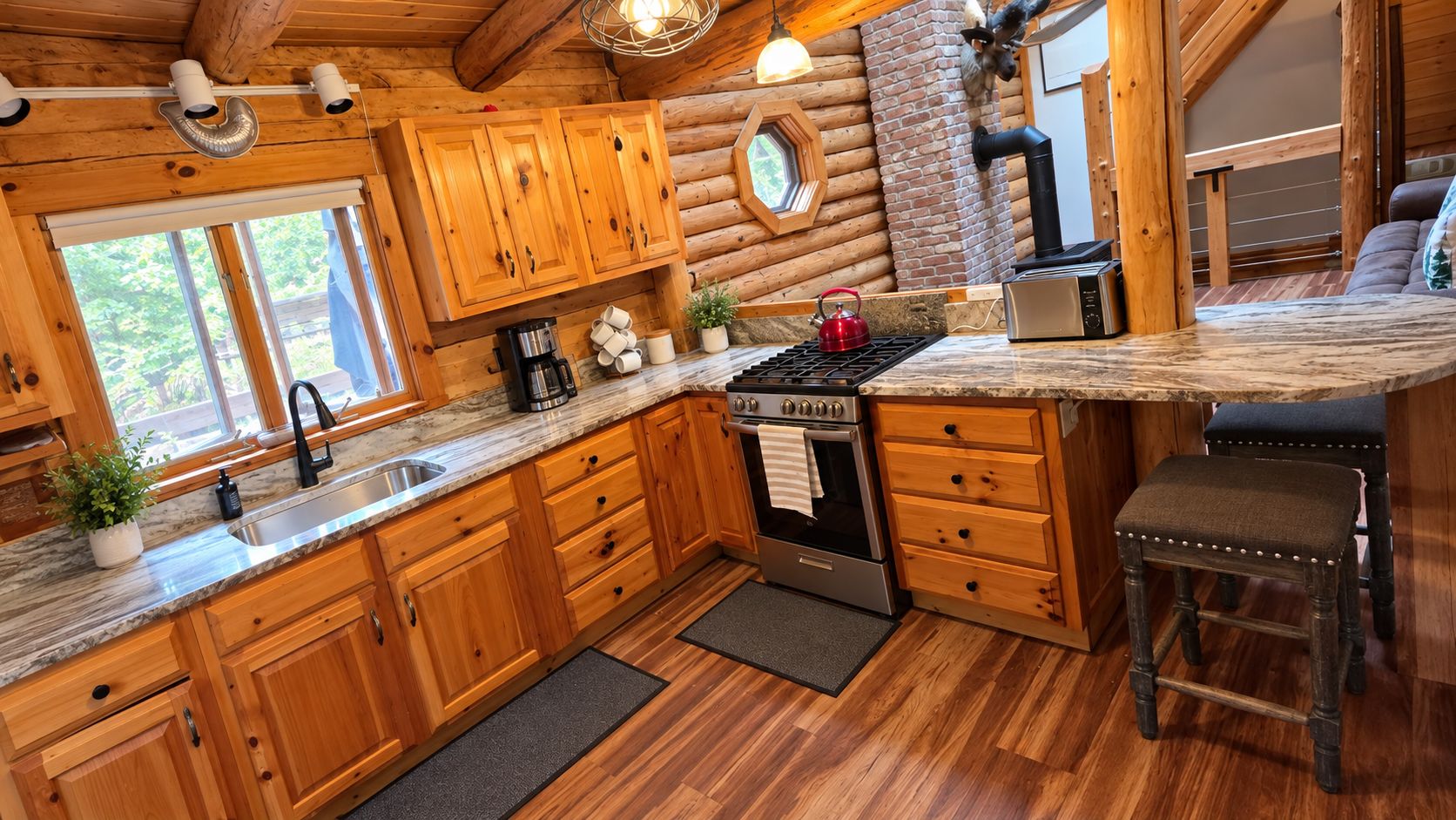 Una cocina tipo cabaña con armarios de madera, estufa integrada y un ventanal grande.