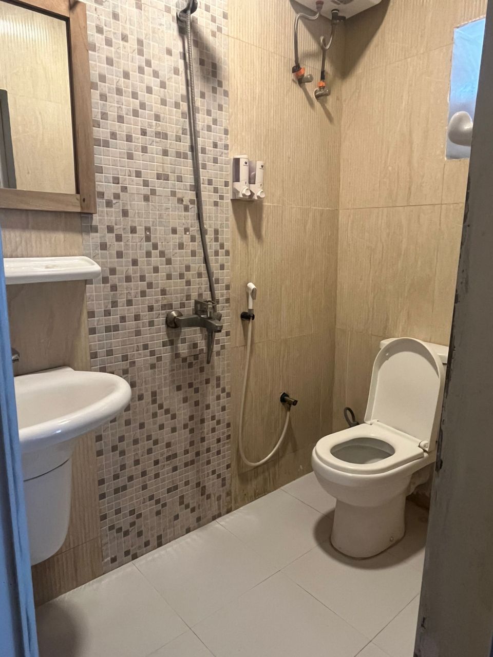 A bathroom with a toilet, a shower, and a sink.