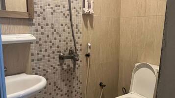 A bathroom with a toilet, a shower, and a sink.