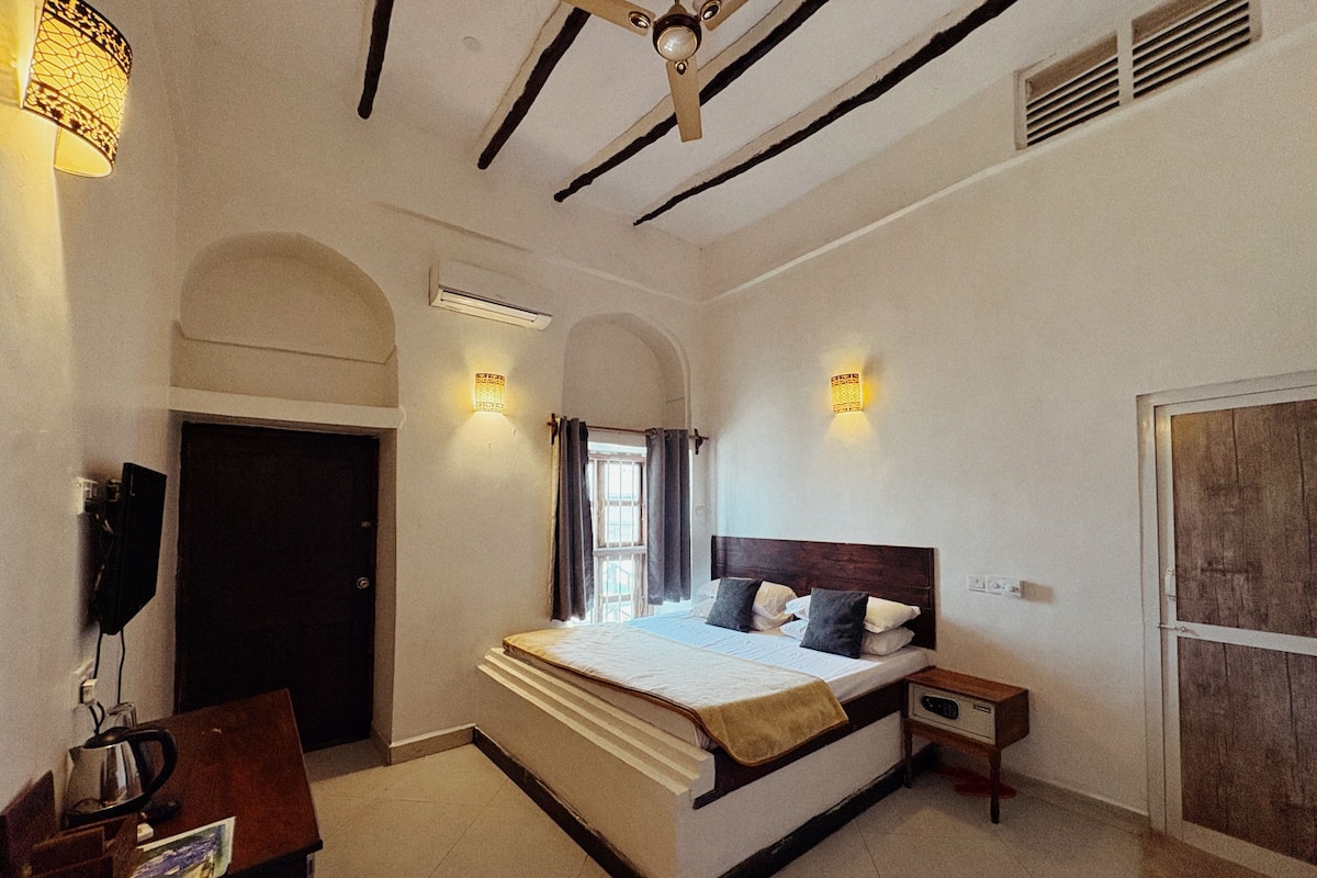 Une chambre à coucher avec un lit, une table de chevet, une lampe et une porte.