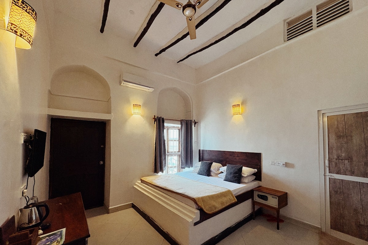 Une chambre à coucher avec un lit, une table de chevet, une lampe et une porte.