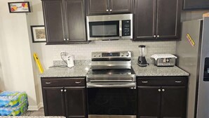 A kitchen with dark cabinets, a microwave, an oven, a toaster, and a refrigerator. - Charming Home in La Vergne | Chill and Relax (La Vergne)
