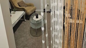 A room with a patterned armchair, a glass coffee table, and a decorative white curtain. - Charming Home in La Vergne | Chill and Relax (La Vergne)