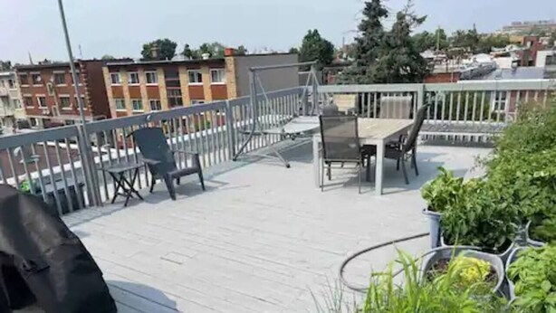 Eine Dachterrasse mit überdachter Sitzecke, einem Grill und Kübelpflanzen.