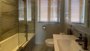 Ein modernes Badezimmer mit einer Glaskabine, einer Toilette und einem großen Waschbecken.