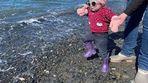 Un bambino su una spiaggia rocciosa con l'oceano sullo sfondo.