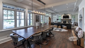 A spacious kitchen with a long wooden table, bar stools, and a modern chandelier. - 6 bed 4 bath cottage on Lake Rosseau with boathouse and sandy beach! (Port Carling)