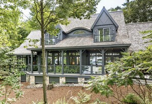 Una casa moderna con un ampio portico, fondamenta in pietra e una zona coperta con finestre.