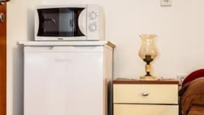 A compact kitchenette with a microwave, a small refrigerator, and a bedside table with a lamp.