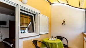 A small room with a table and two chairs, a window with blinds, and a yellow awning.