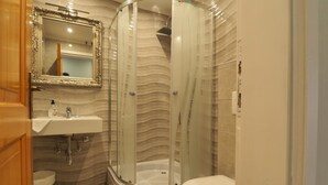 Et moderne badeværelse med en brusekabine i glas, en hvid vask og et toilet.