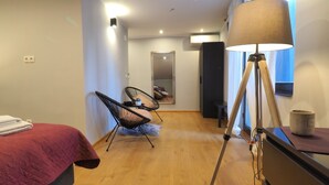 Ein modernes Schlafzimmer mit einem Bett, zwei Stühlen, einer Lampe und einem Spiegel.