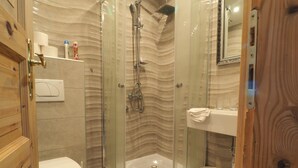 Ein modernes Badezimmer mit einer Duschkabine, einer Toilette und einem Waschbecken inklusive Spiegel.