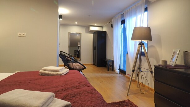 Ein modernes Schlafzimmer mit einem großen Bett, einem Sessel, einem Schreibtisch und einer Lampe.