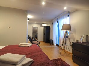Ein modernes Schlafzimmer mit einem großen Bett, einem Sessel, einem Schreibtisch und einer Lampe.