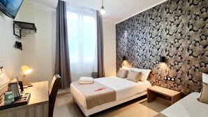 Une chambre d’hôtel avec un grand lit, des tables de chevet, un bureau, une chaise et un mur décoré d’un motif.