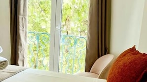 Une chambre d’hôtel avec un lit, des rideaux et une vue sur la verdure.