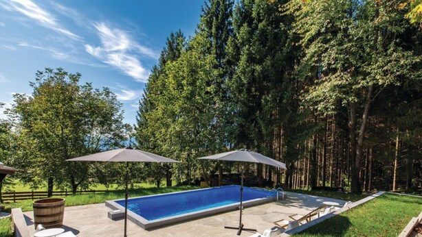 A rectangular swimming pool with two umbrellas, surrounded by a concrete deck, with a wooden barrel and lounge chairs on one side. - Apartments & Rooms Latin - Quadruple Room (Plaski)