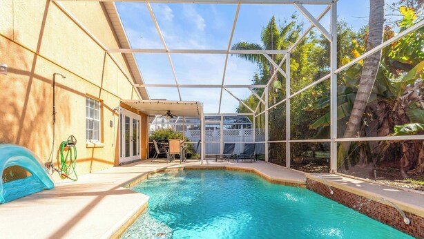 Ein Swimmingpool mit Glasveranda, umgeben von einer Terrasse mit Stühlen und einem Tisch.