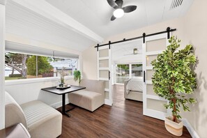 A modern room with a sofa, a small table, a ceiling fan, a window with a view, and a plant. - Luxury Home on Dora Lake – 2 Min to Downtown Mount Dora (Mount Dora)