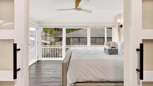 A bedroom with a bed, a ceiling fan, a window with a view of the outside, and a balcony with a railing. - Luxury Home on Dora Lake – 2 Min to Downtown Mount Dora (Mount Dora)