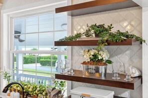 A kitchen with a window, a shelf with a flower pot, and a white cabinet. - Luxury Home on Dora Lake – 2 Min to Downtown Mount Dora (Mount Dora)