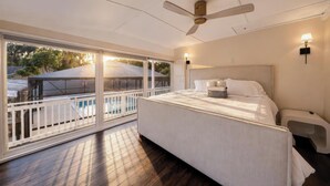 A bedroom with a large bed, a ceiling fan, a nightstand, and a view of a pool through a sliding glass door. - Luxury Home on Dora Lake – 2 Min to Downtown Mount Dora (Mount Dora)