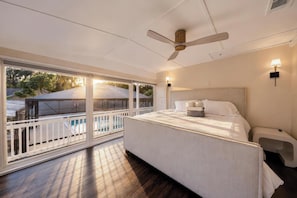 A bedroom with a large bed, a ceiling fan, a nightstand, and a view of a pool through a sliding glass door. - Luxury Home on Dora Lake – 2 Min to Downtown Mount Dora (Mount Dora)