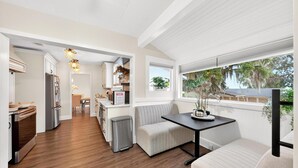 A modern kitchen with wooden flooring, a dining area with a bench, and a view of the outdoors. - Luxury Home on Dora Lake – 2 Min to Downtown Mount Dora (Mount Dora)