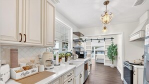 A modern kitchen with white cabinetry, a coffee bar, and a chandelier. - Luxury Home on Dora Lake – 2 Min to Downtown Mount Dora (Mount Dora)