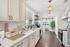 A modern kitchen with white cabinetry, a coffee bar, and a chandelier. - Luxury Home on Dora Lake – 2 Min to Downtown Mount Dora (Mount Dora)