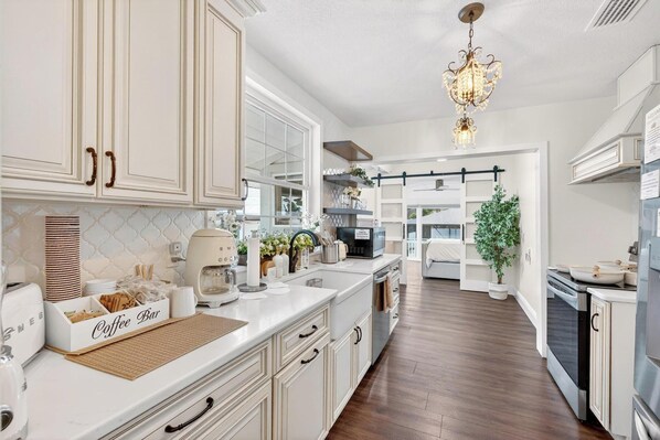 A modern kitchen with white cabinetry, a coffee bar, and a chandelier. - Luxury Home on Dora Lake – 2 Min to Downtown Mount Dora (Mount Dora)