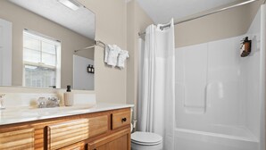 A modern bathroom with a wooden vanity, a white toilet, and a glass shower enclosure.