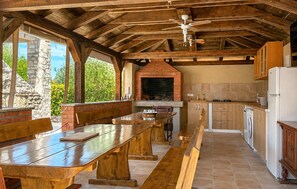 An outdoor kitchen with a brick oven, wooden benches, and a ceiling fan. - Beautiful home in Vir (Vir)